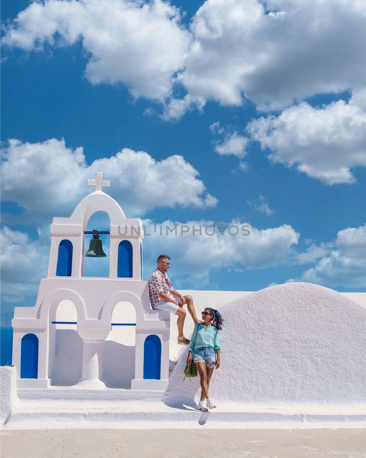 A couple visit Santorini Greece, men and women visit the whitewashed Greek village of Oia during summer vacation summer holidays in Europe