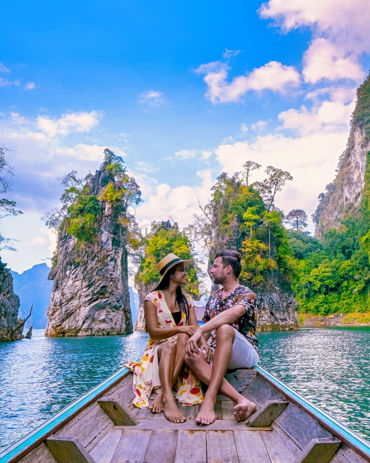 a couple traveling by longtail boat exploring epic limestone cliffs in a huge lake in Khao Sok National Park, Chiew lan lake, Thailand Surat Thani