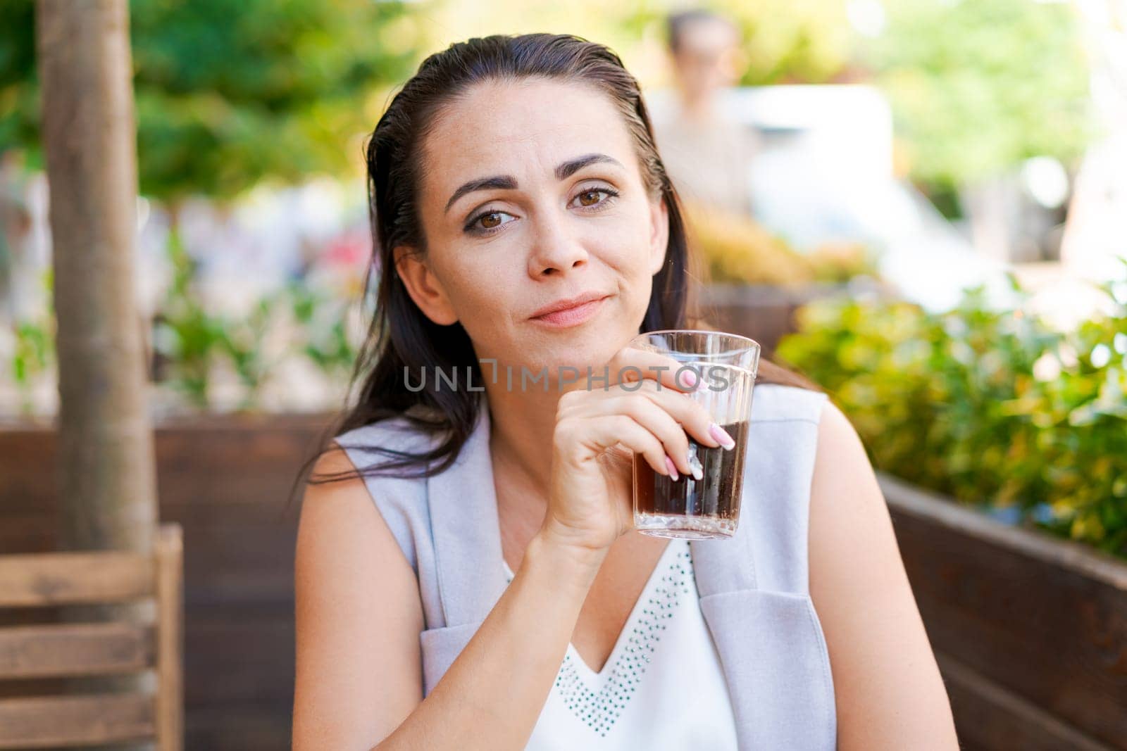 Happy business woman in street cafe drinks natural juice and smiles on sunny day