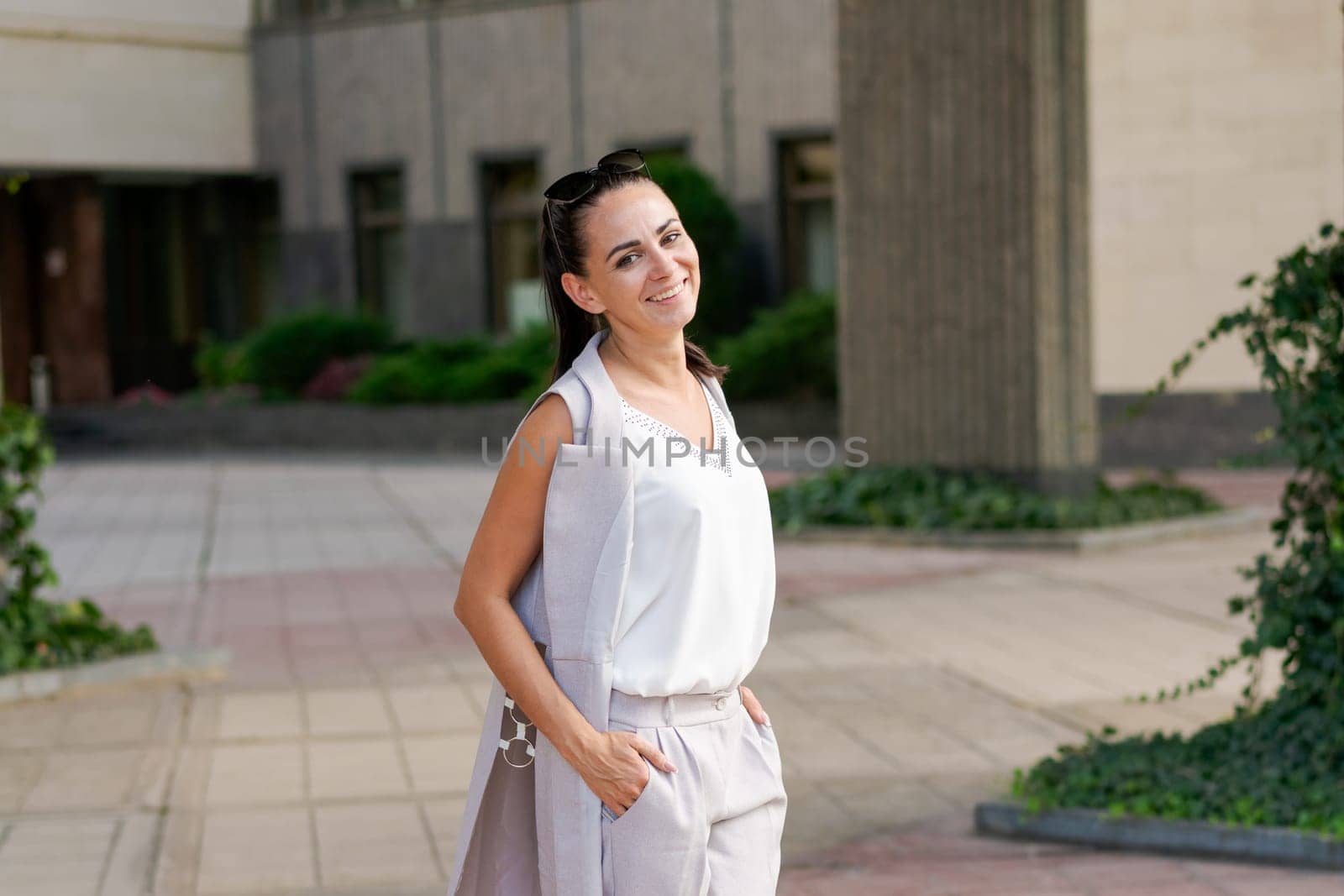 Confident smiling businesswoman standing on the street, portrait. Proud successful female entrepreneur in suit posing while looking at camera outdoors.