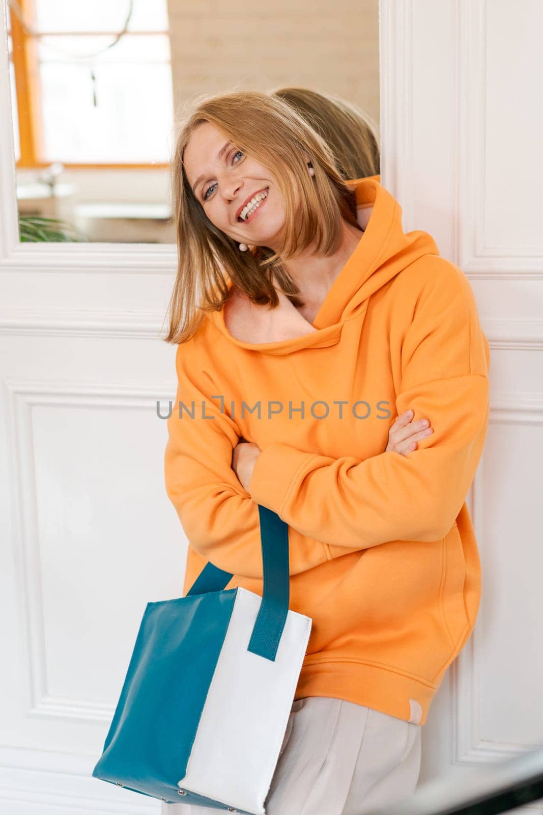 Portrait happy woman in cafe. Wearing a bright orange sweatshirt. by EkaterinaPereslavtseva