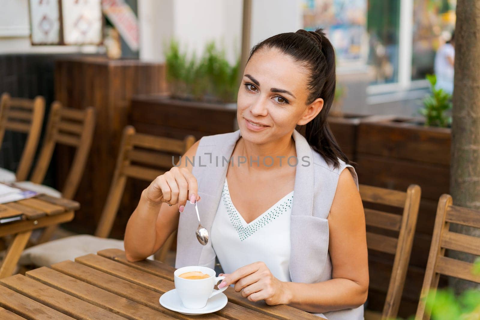 Happy smiling business brunette drinking coffee in a street cafe. Coffee break by EkaterinaPereslavtseva