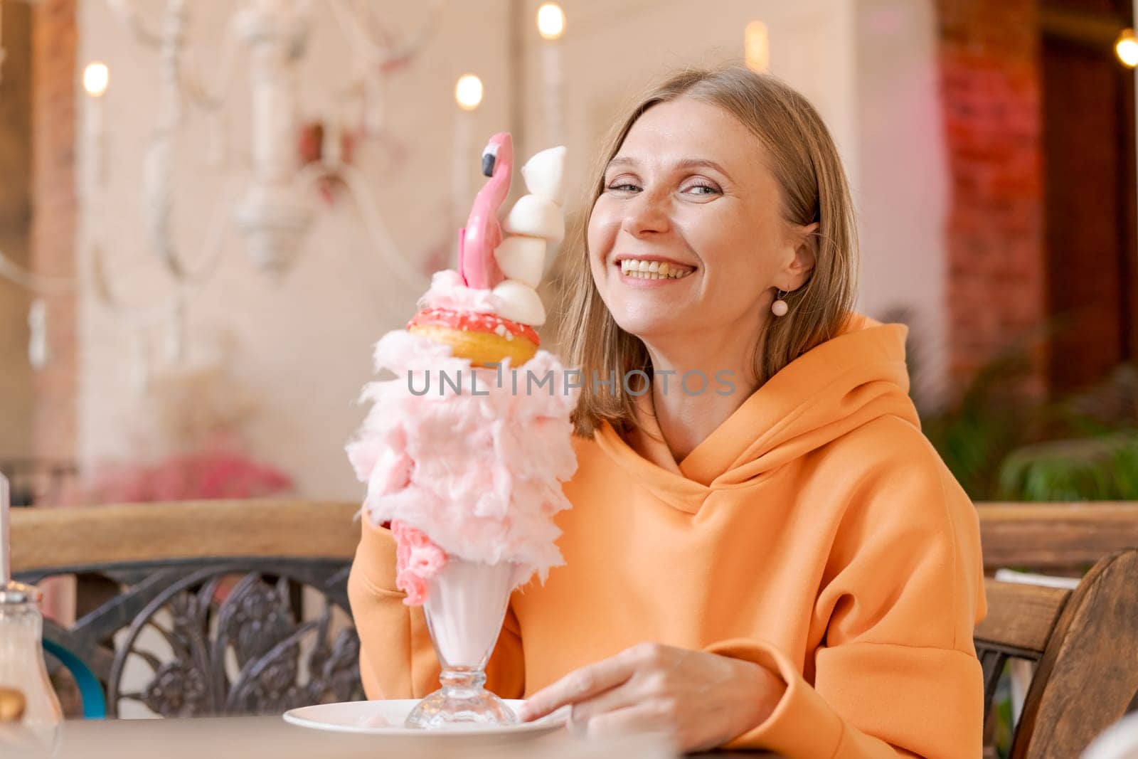Happy woman eating sweet dessert in form pink flamingo in restaurant, woman by EkaterinaPereslavtseva