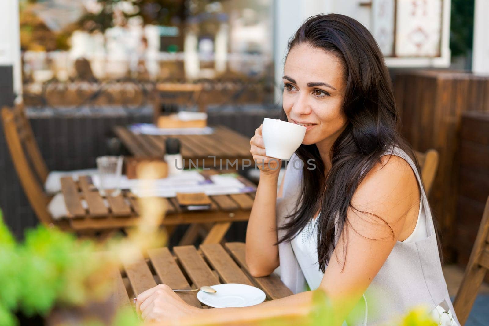 Happy smiling business brunette drinking coffee in a street cafe. Coffee break by EkaterinaPereslavtseva