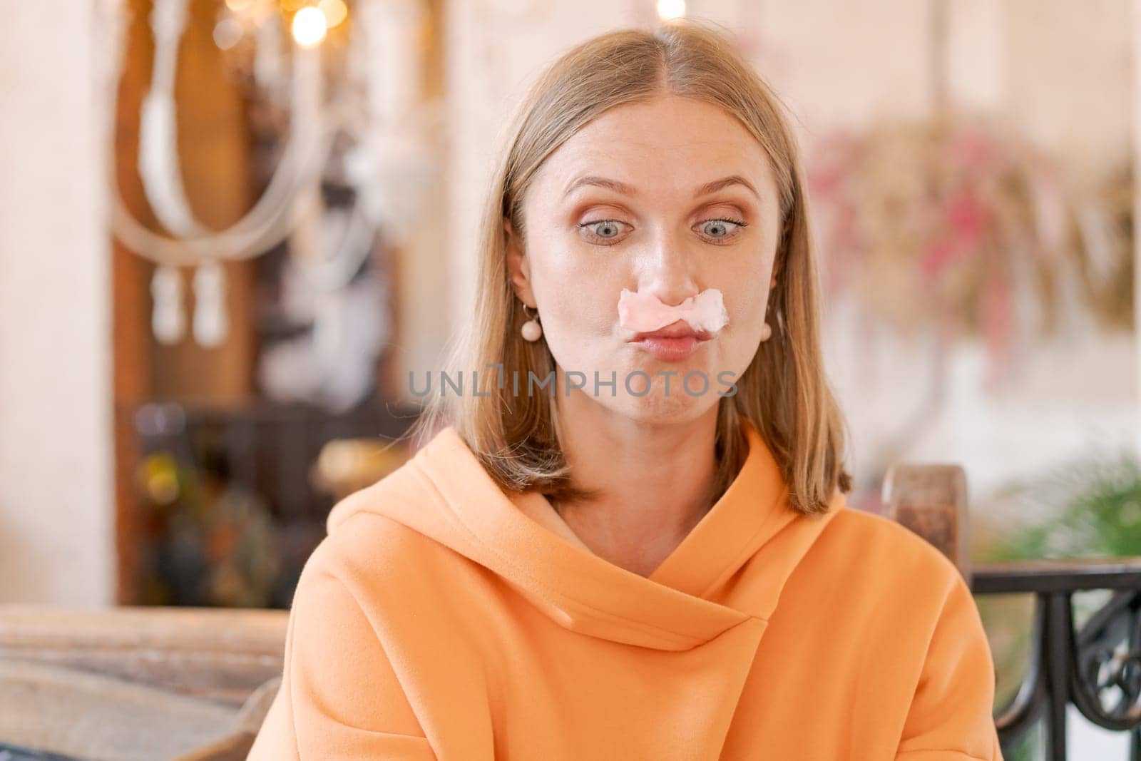 Happy woman eating sweet dessert in form pink flamingo in restaurant, woman sitting in a cafe and enjoying a sweet dessert for lunch, sweet tooth concept