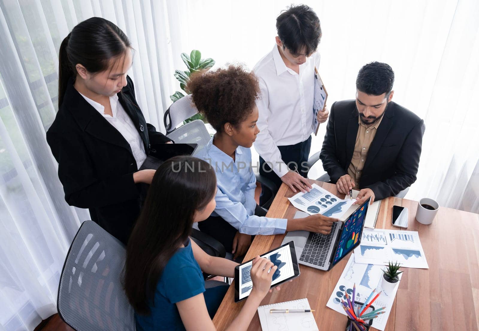 Multiracial analyst team use BI Fintech software to analyze financial data on meeting table. Financial dashboard data display on laptop screen with analyzed chart for marketing indication. Concord