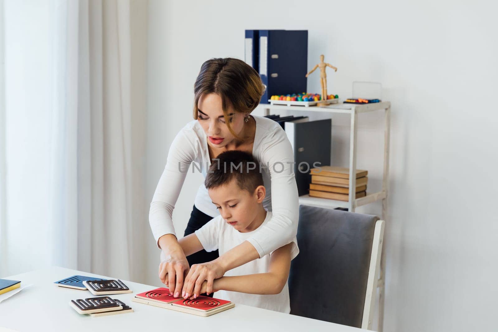 Woman playing with boy in educational educational games at school by Simakov