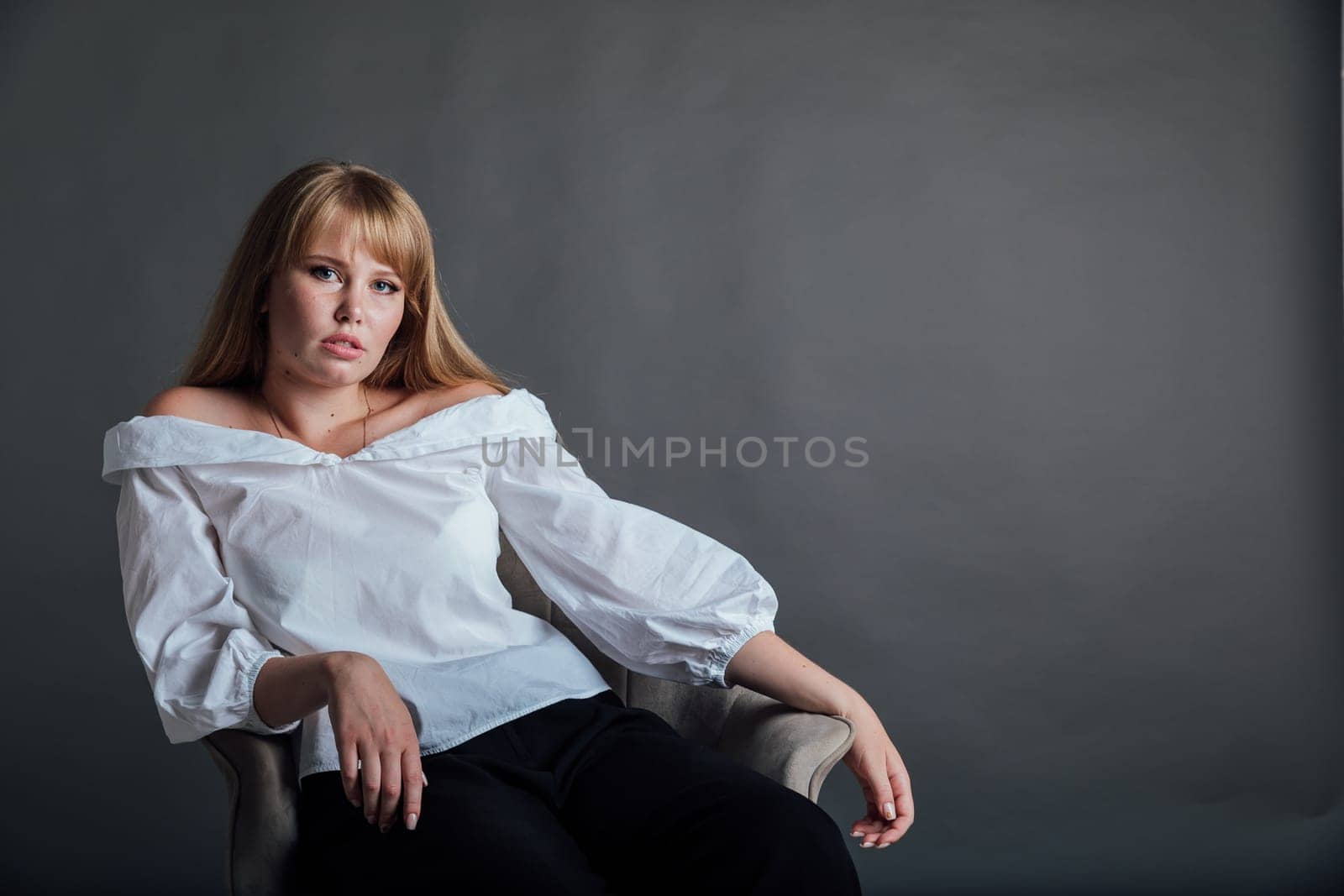 Beautiful young woman in white blouse and black pants sitting by Simakov