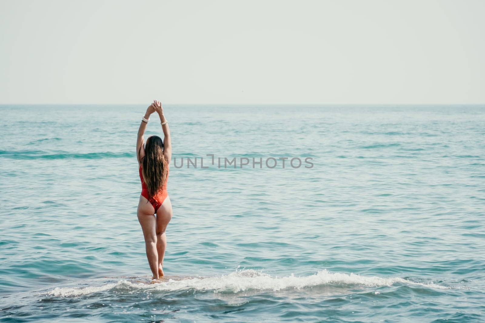 Woman sea yoga. Back view of free calm happy satisfied woman with long hair standing on top rock with yoga position against of sky by the sea. Healthy lifestyle outdoors in nature, fitness concept by panophotograph