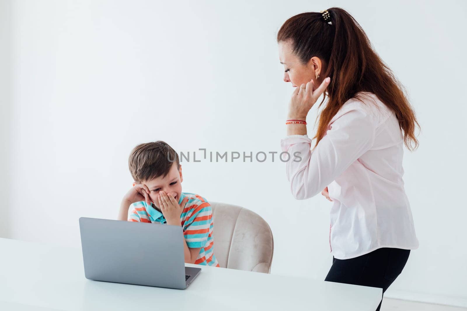 Woman teaching boy on laptop in school