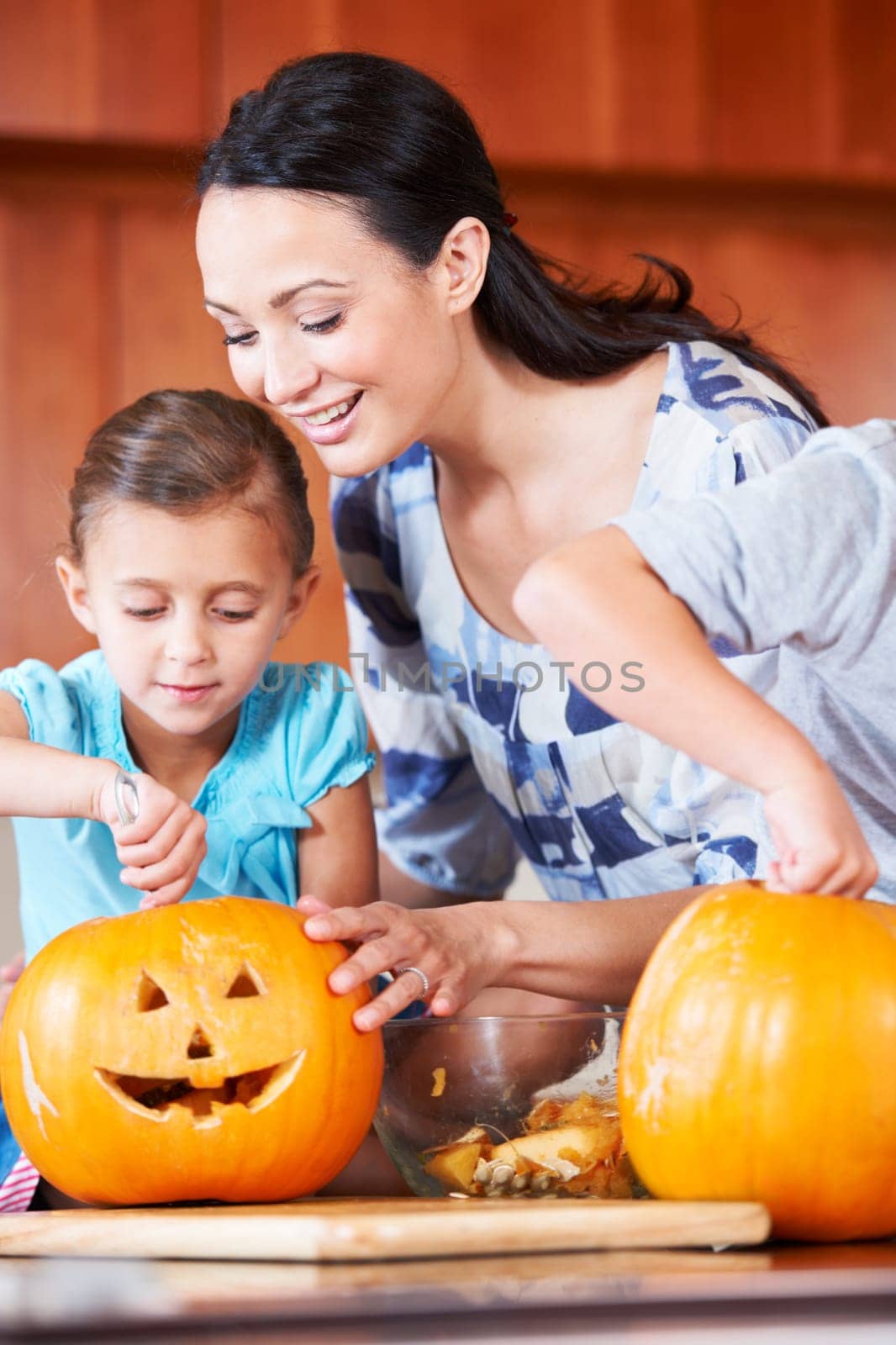 Halloween, pumpkin and mother with child in the kitchen for holiday celebration at home. Creative, smile and happy mom with girl kid bonding and carving vegetable for decoration or tradition at house by YuriArcurs