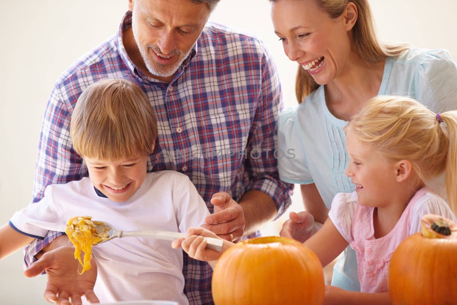 Halloween, family fun and carving a pumpkin with children in a home for bonding and helping with craft. Man and woman or parents and young kids together for creativity, holiday lantern and happy.