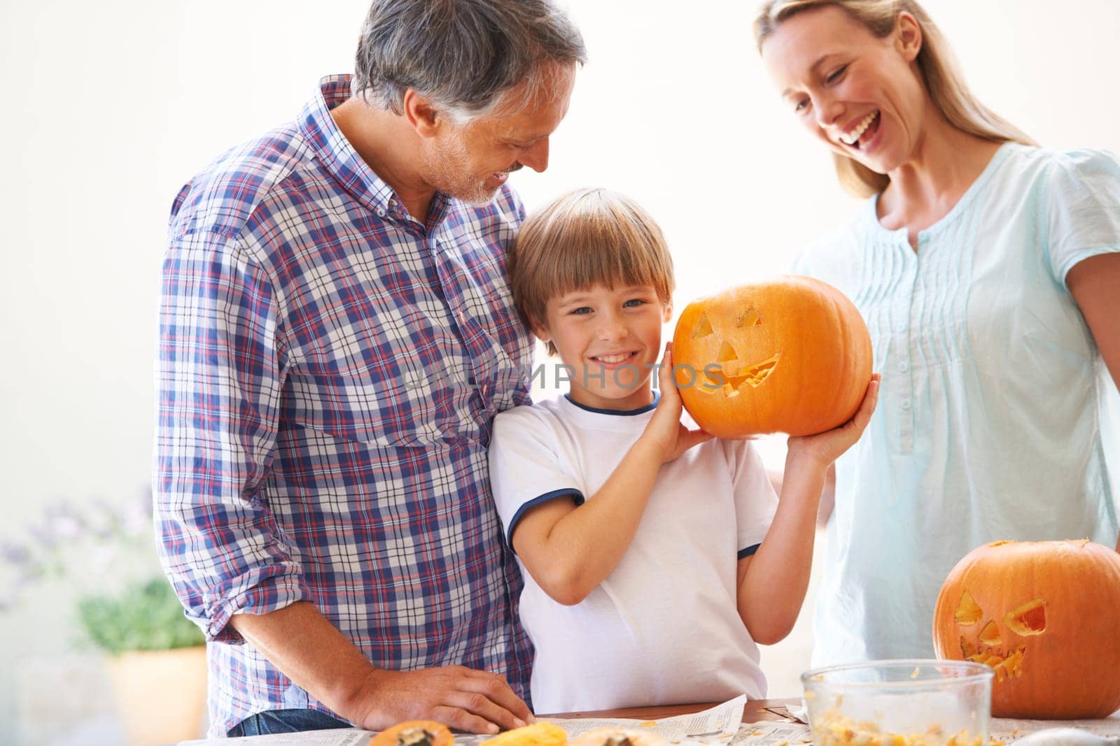 Halloween, family and carving a pumpkin with a child in a home for fun and bonding. Man and woman or parents and young kid for portrait together for creativity, holiday lantern and happy craft.
