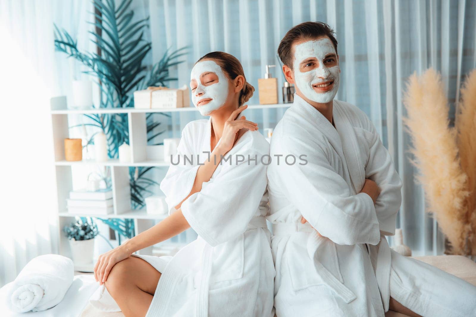 Blissful couple in bathrobe with facial cream mask enjoying serene ambiance of spa salon resort or hotel during holiday. Pampering face spa and skincare treatment with essence relaxation. Quiescent