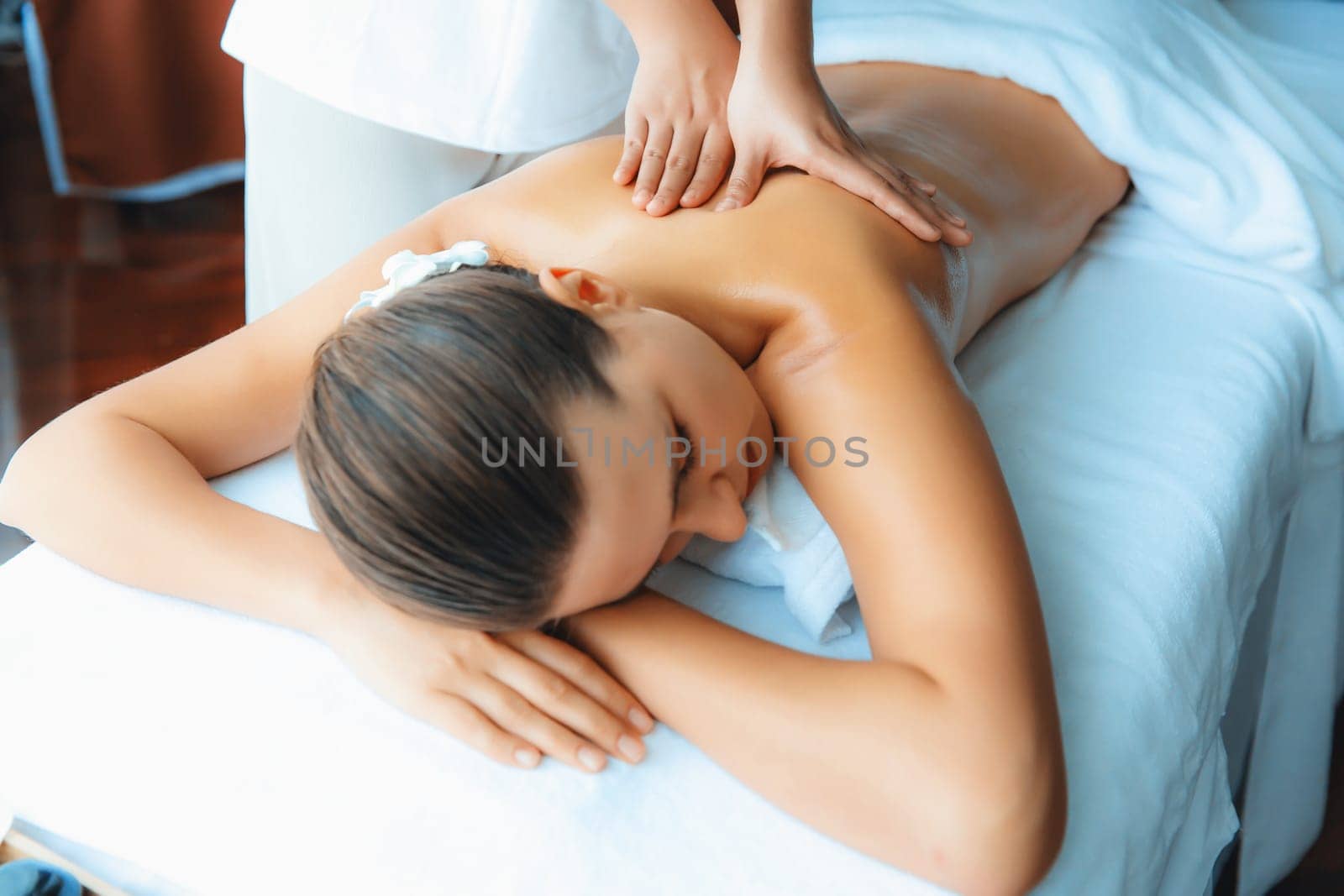 Caucasian woman customer enjoying relaxing anti-stress spa massage and pampering with beauty skin recreation leisure in day light ambient salon spa at luxury resort or hotel. Quiescent