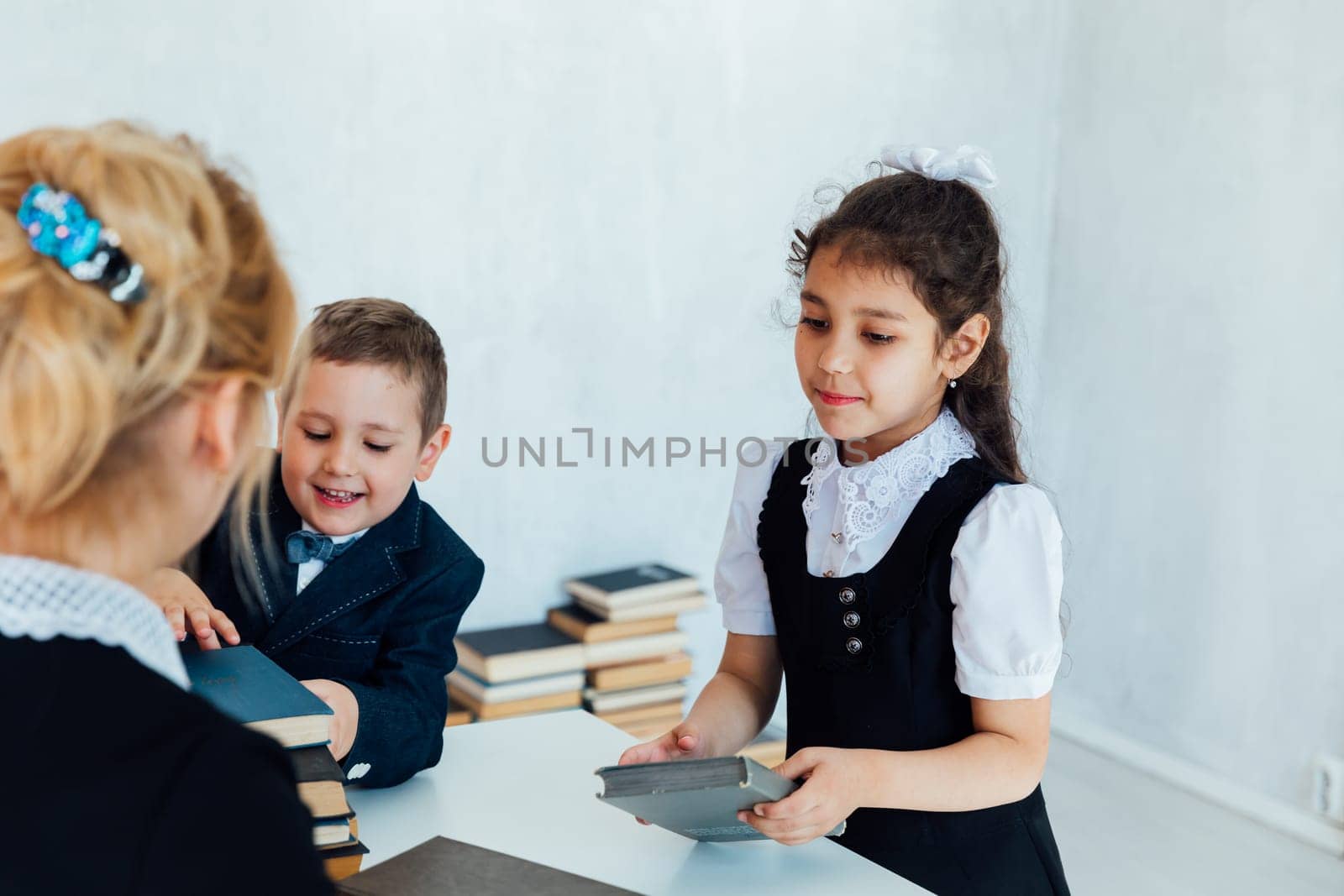 Female teacher teaching children boy and girl in school classroom