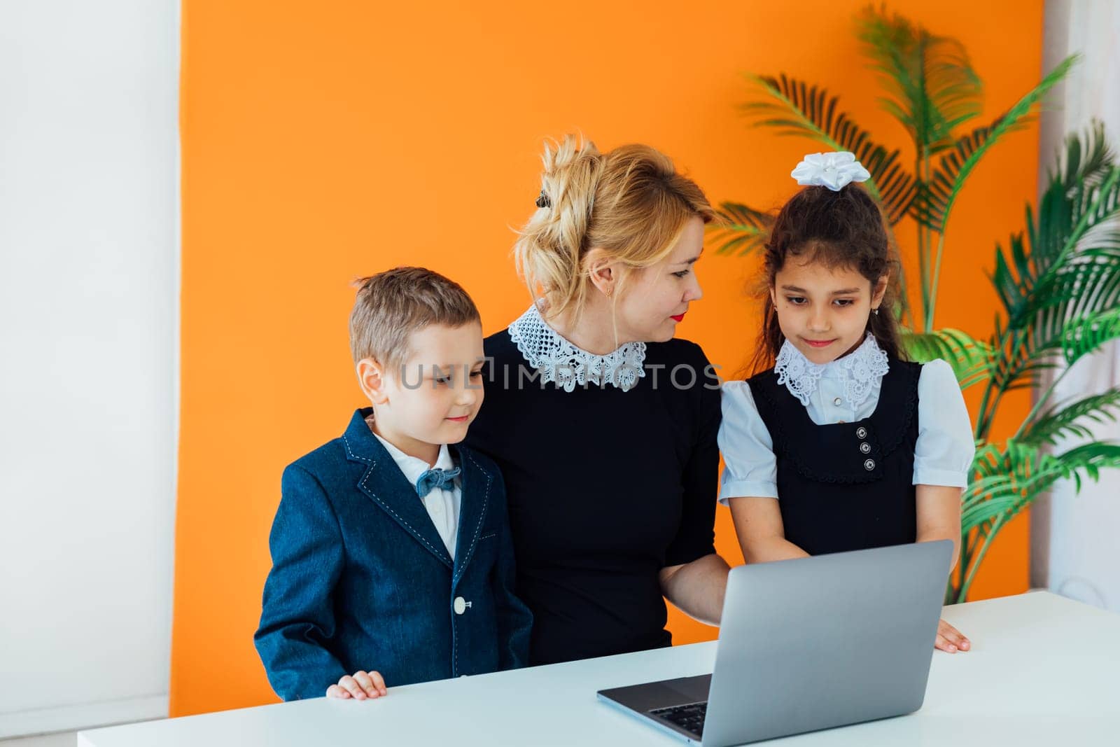 Teacher teaching kids on laptop at school by Simakov
