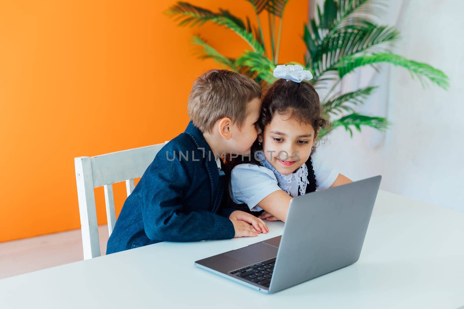 Boy and girl sitting at desk with laptop by Simakov