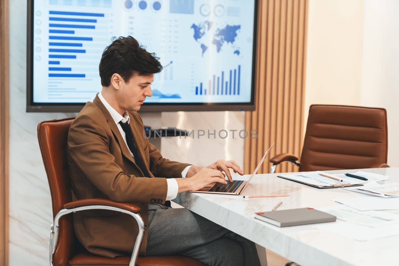 Professional businessman analysis data by using laptop at meeting. Project manager looking at laptop on meeting table while projector displayed graph and financial statistic with document. Ornamented.