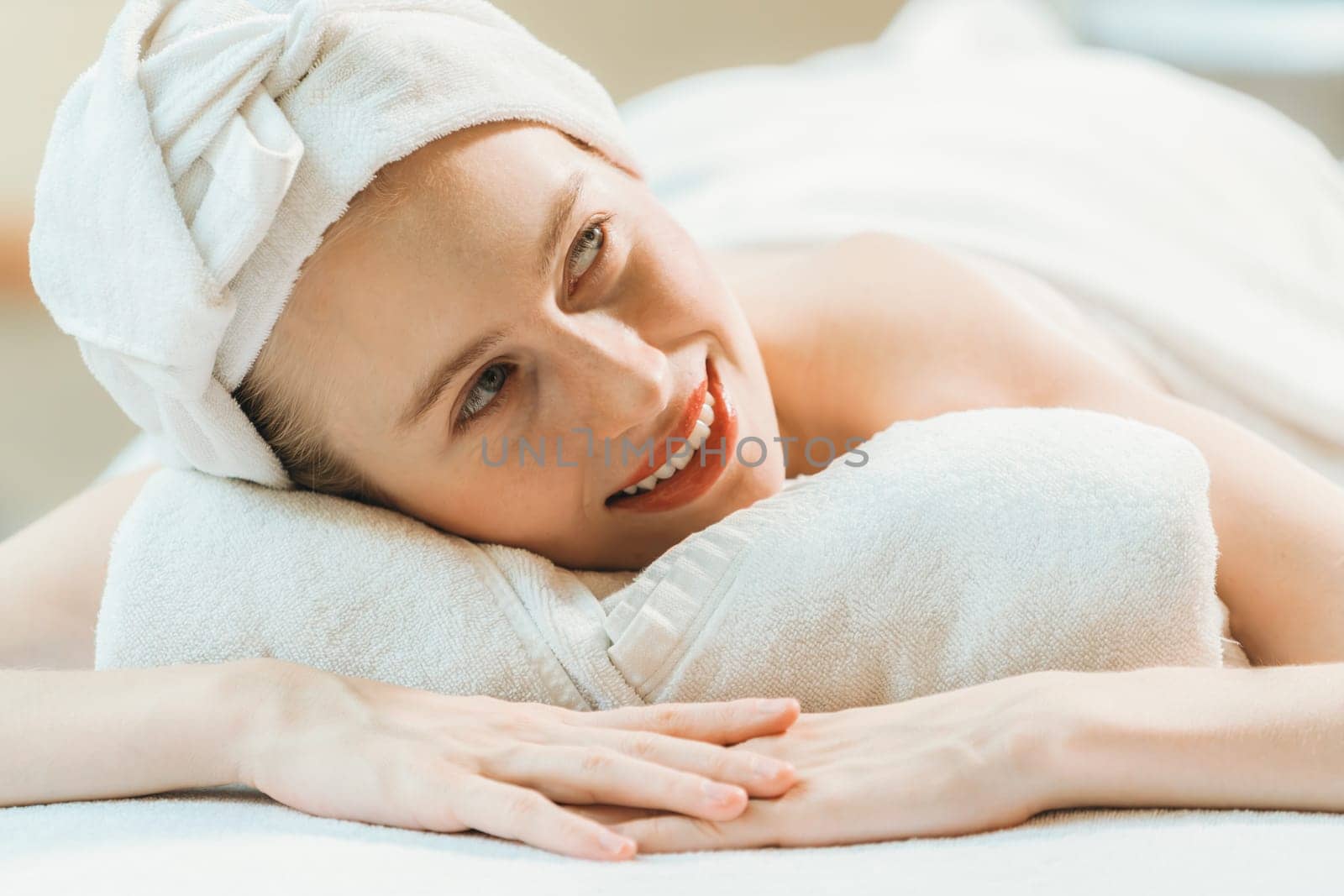 A beautiful young woman lies on a spa bed, her body relaxed and at peace. Pretty caucasian girl surrounded by the spa environment and the gentle aroma of essential oils. Close up. Tranquility.