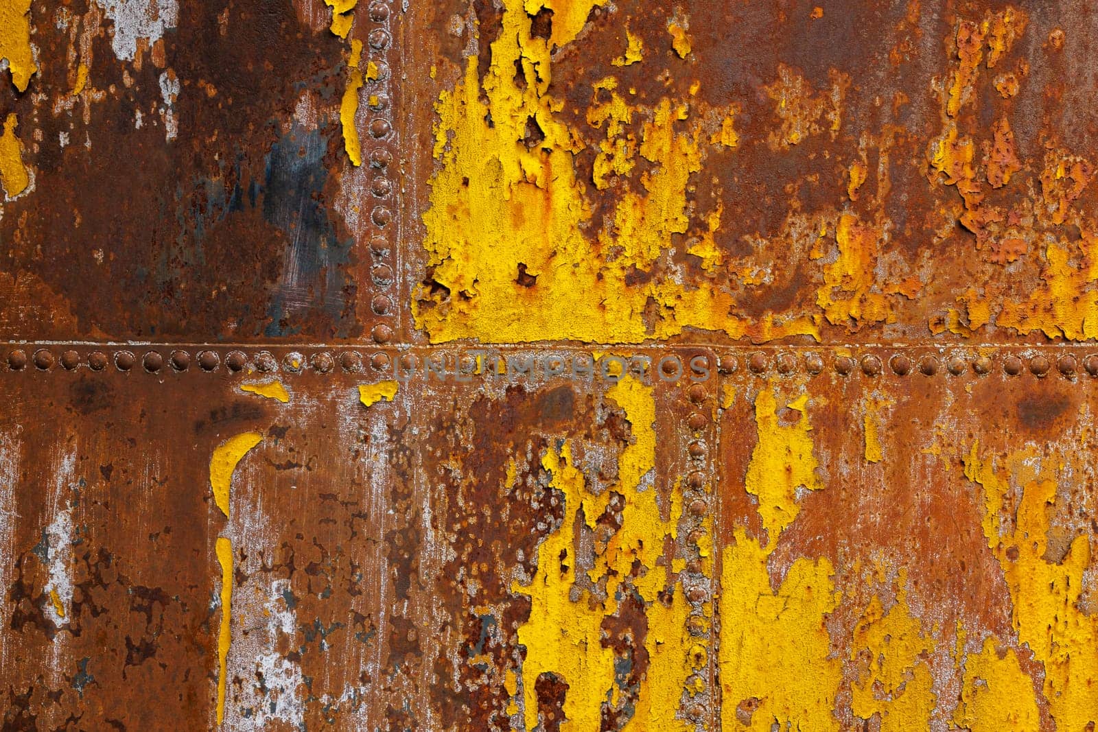 beautifully rusted rivetted sheet metal with leftovers of yellow paint texture and full-frame background by z1b