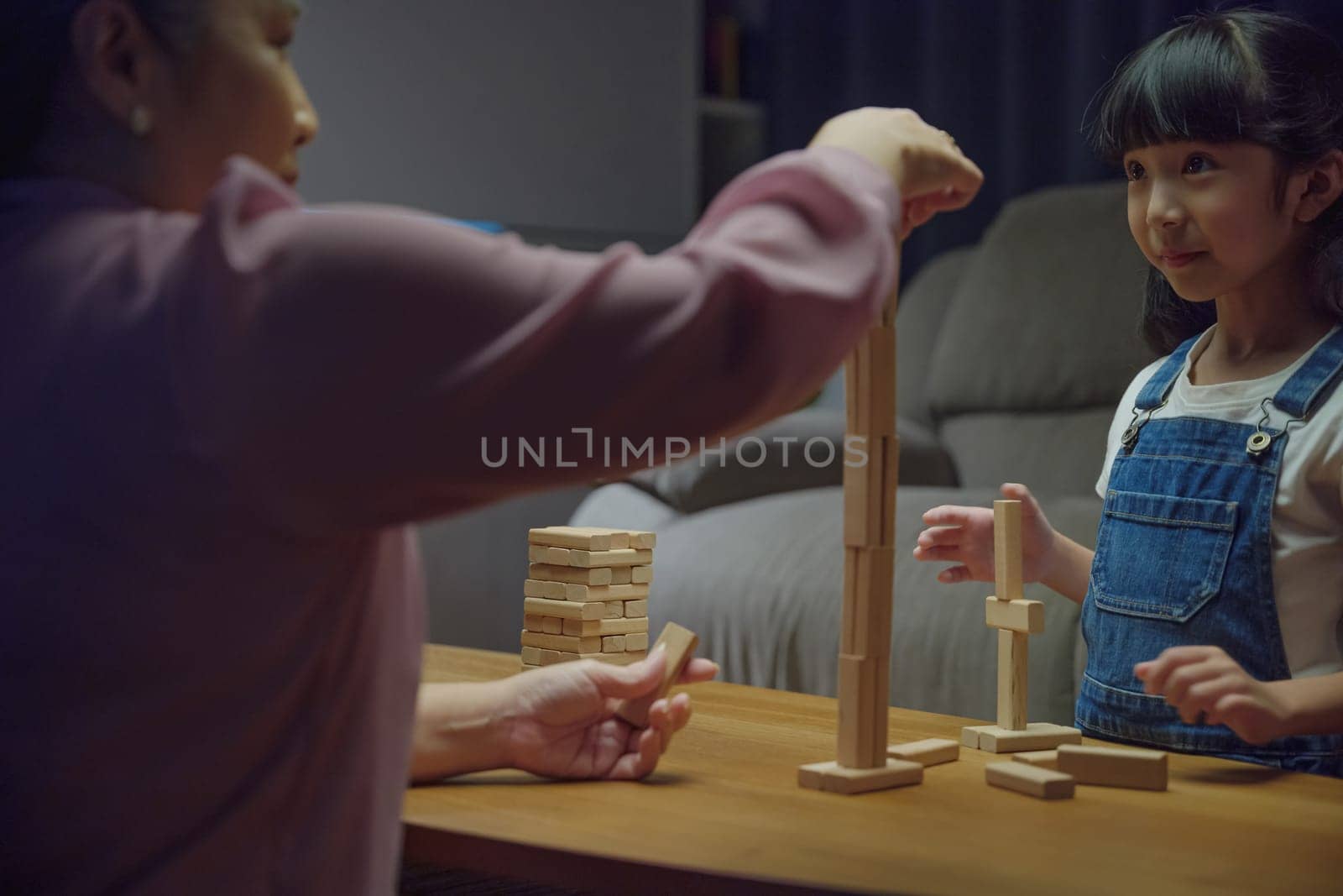 Asian family enjoy playing toy block with little daughter together in home living room by Sorapop