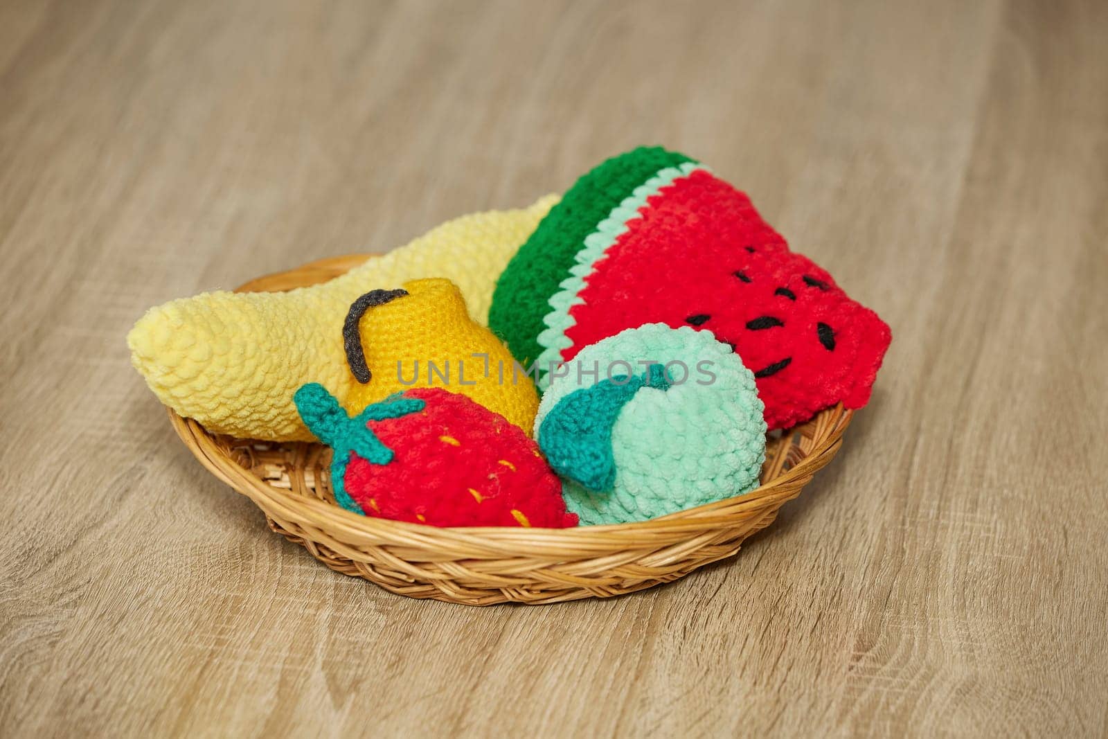 Cute knitted fruits toys on a wicker plate.