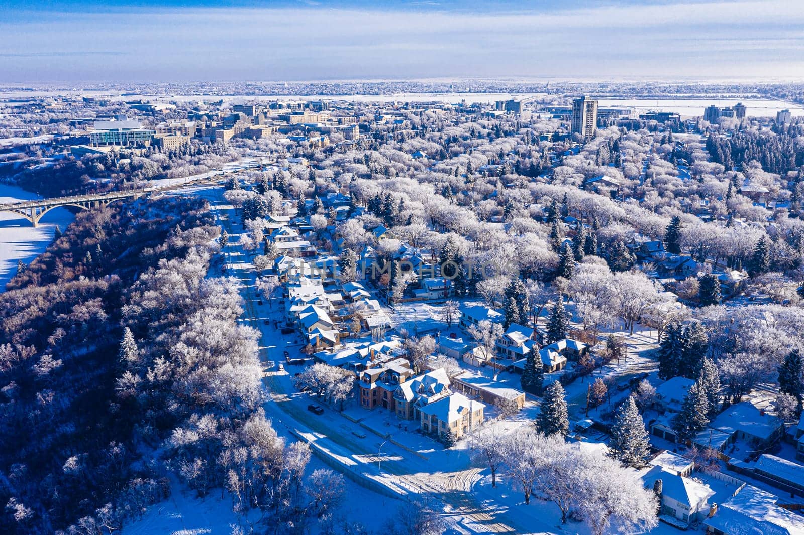 Behold the winter wonderland of Downtown Saskatoon from the sky. This drone image captures the snowy cityscape, frozen river views, and the serene beauty of urban life in the chill of winter.