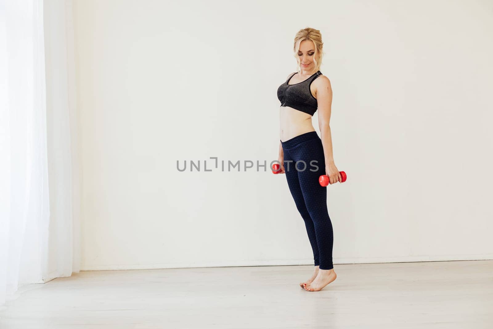 Female athlete engaged in fitness with dumbbells sport by Simakov