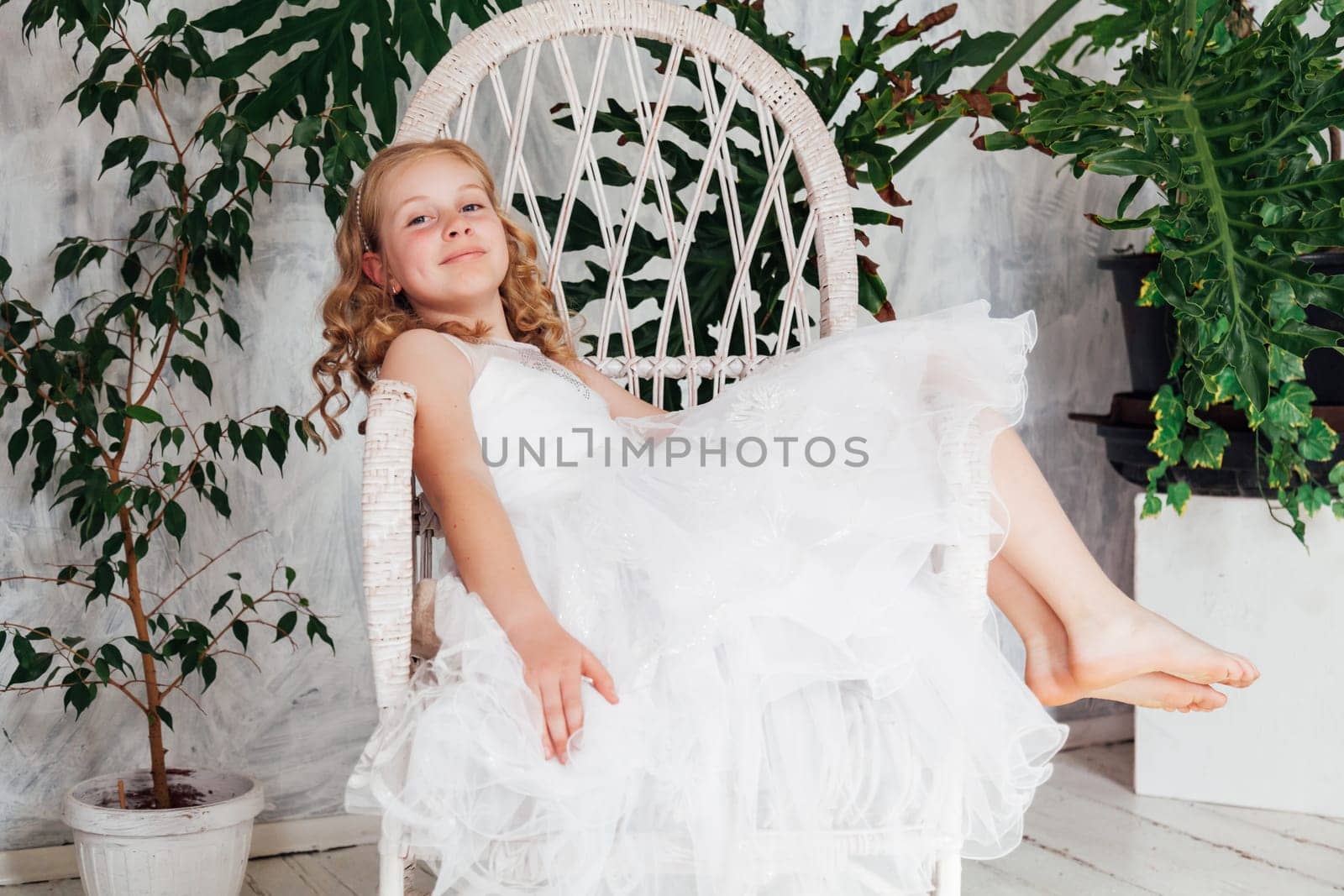 Beautiful blonde girl in white dress sits in a chair by Simakov