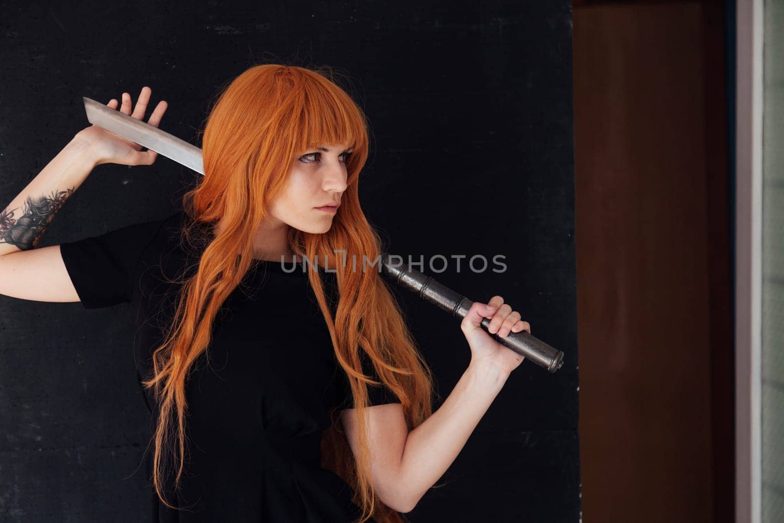 cosplayer anime with red hair holds a Japanese sword