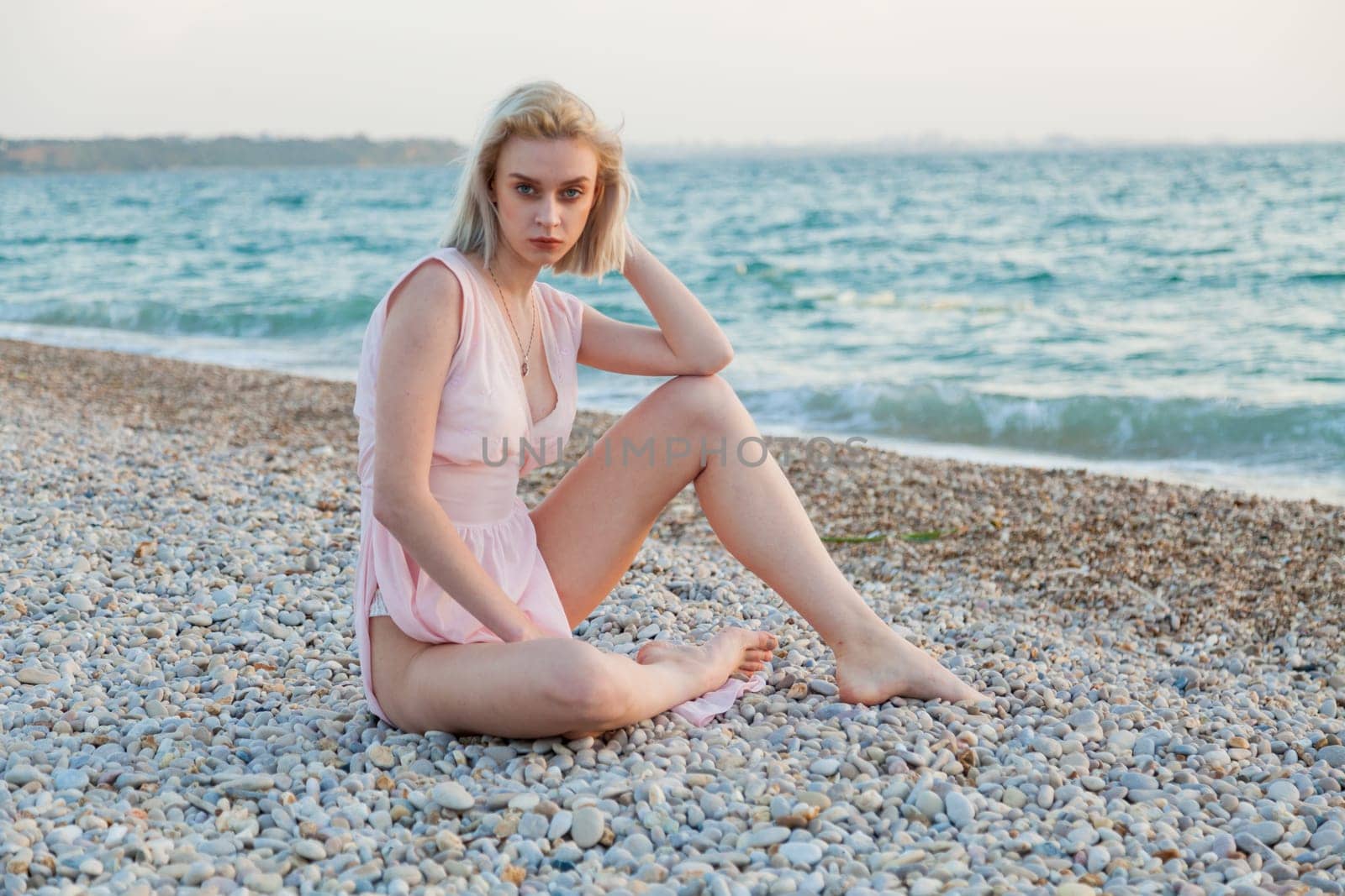 Portrait of a fashionable blonde woman on the beach by the sea