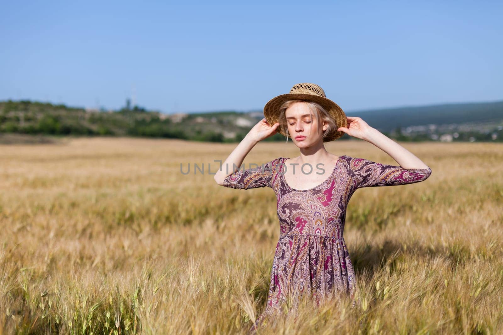 a smoldering fashionable woman in a dress in a field of ripe wheat