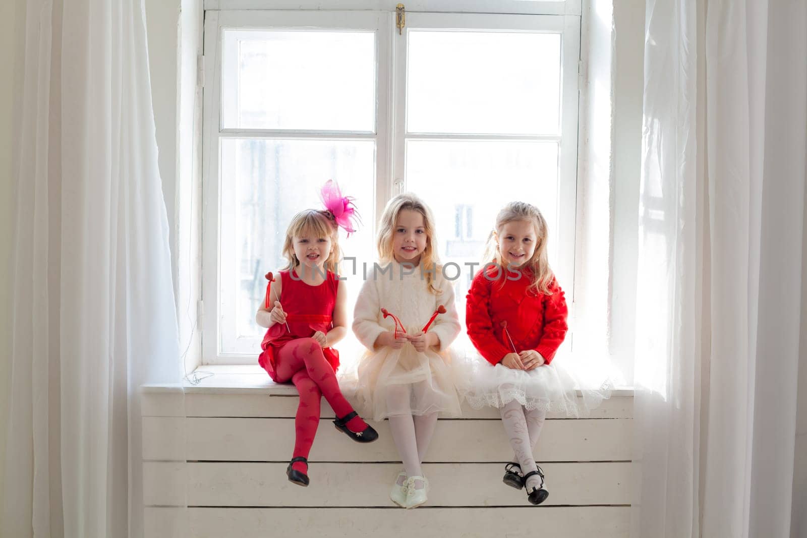 girl girlfriends sit by the window in white and red dresses