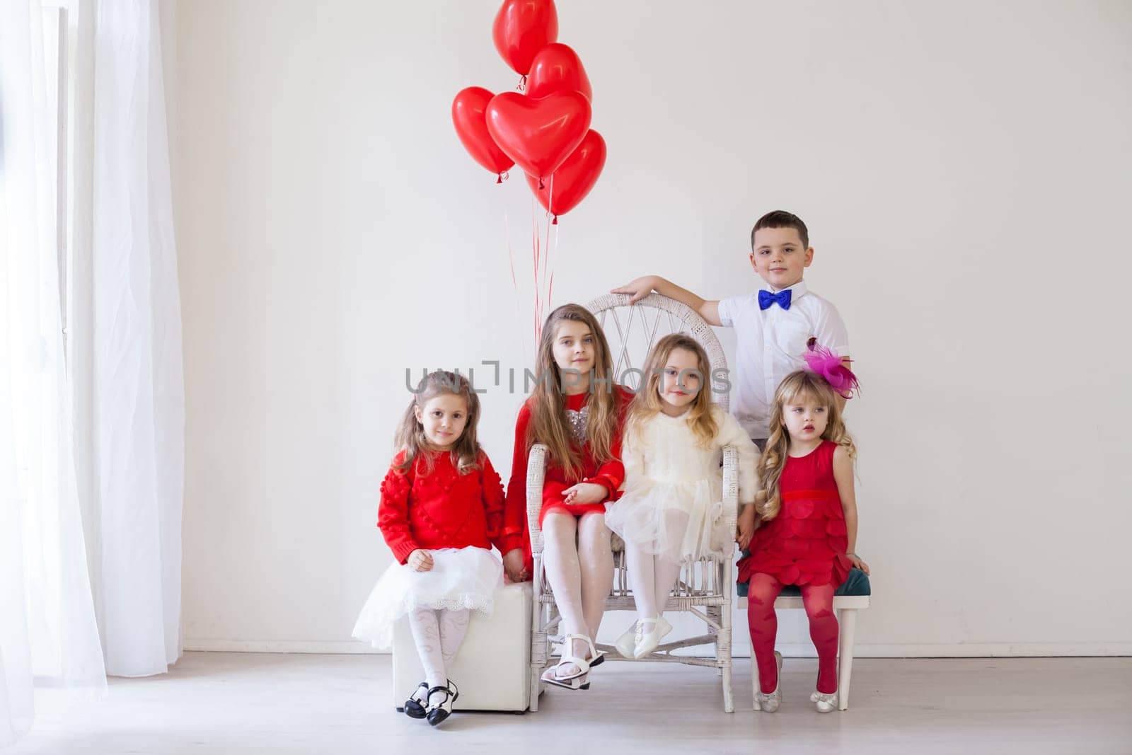 four girls in a white room with red holiday balloons and a boy