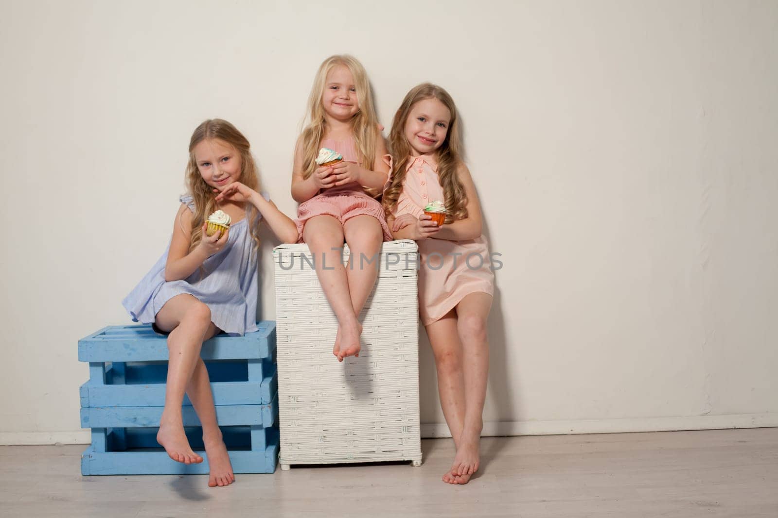 Three fashionable little girls eat candy lollipop by Simakov