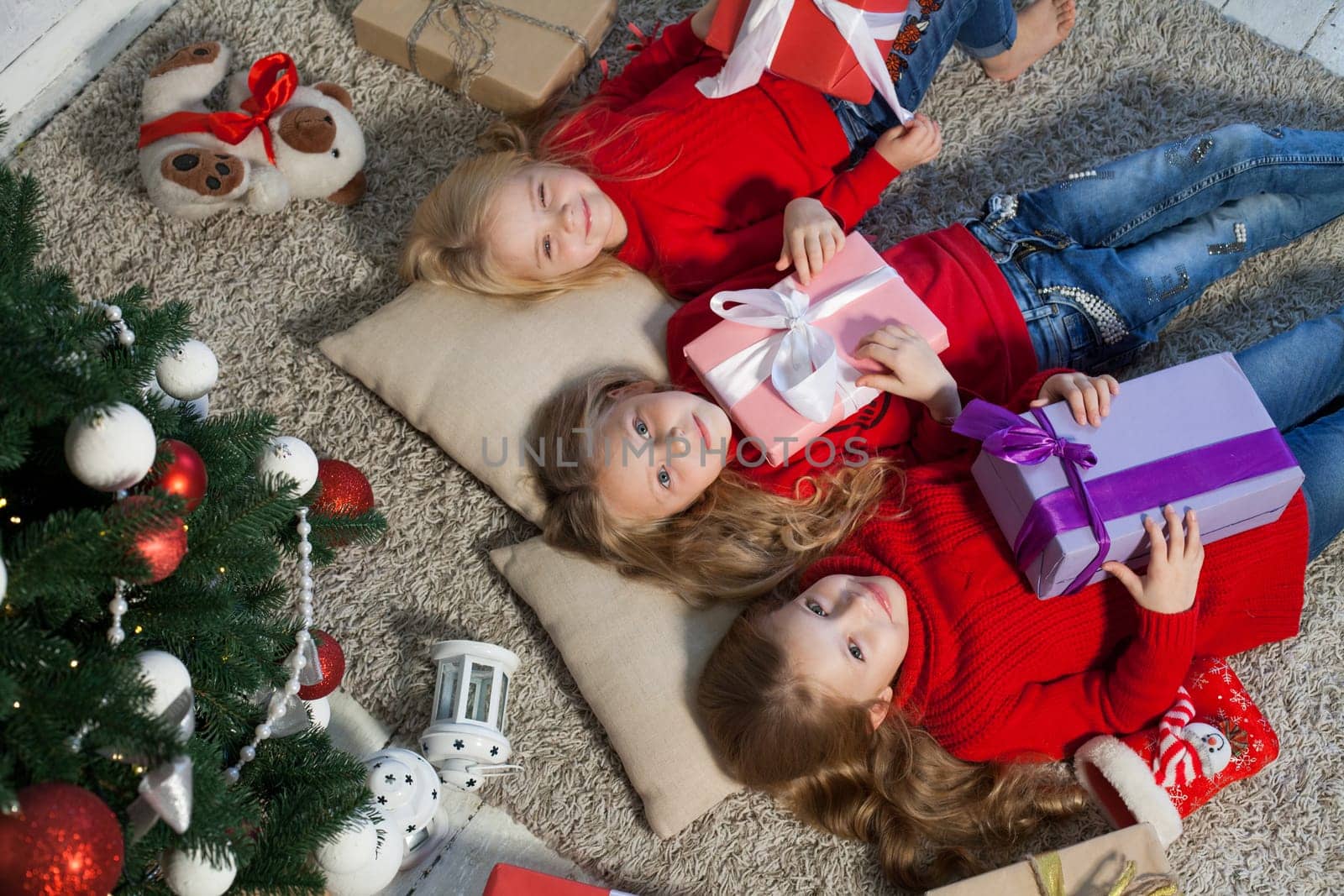 Three little girl girlfriends open Christmas presents to the new year