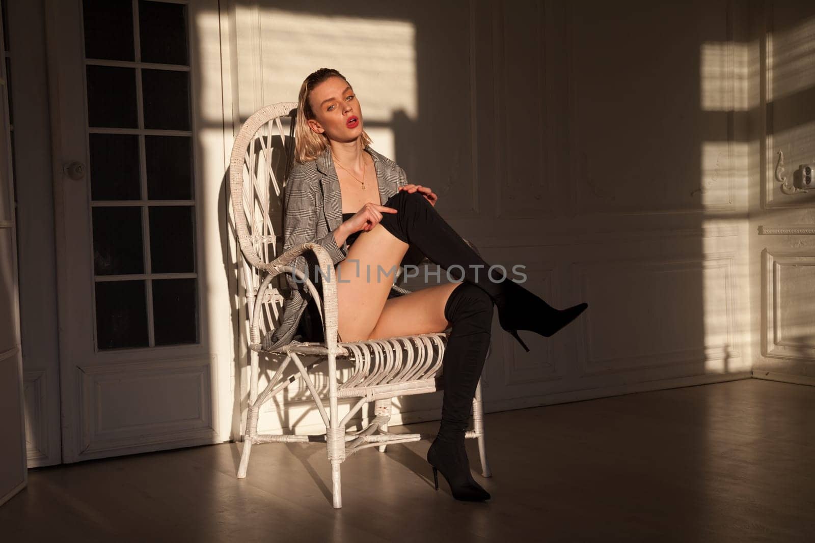 Portrait of a blonde woman sitting in a chair in an empty room