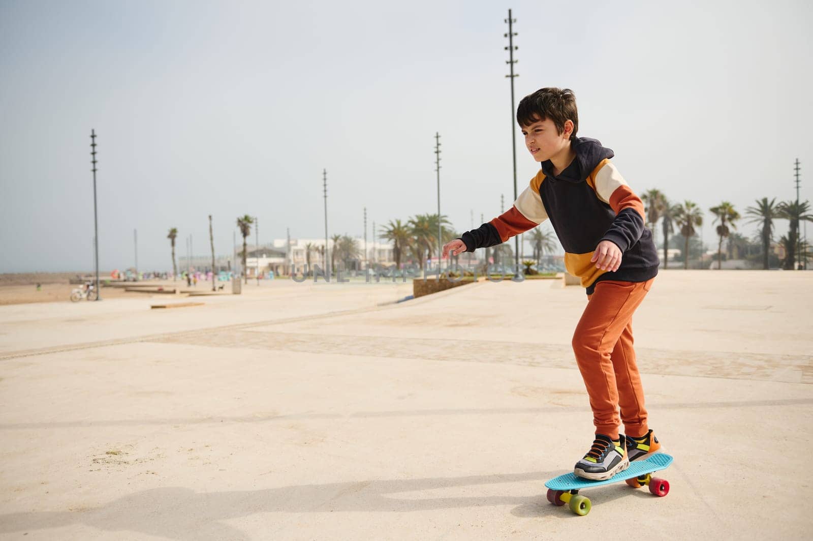 Happy active teenage boy riding on skateboard on an urban skatepark playground, dressed in stylish sportswear. Extreme sport, Happy carefree childhood. Active healthy lifestyle concept