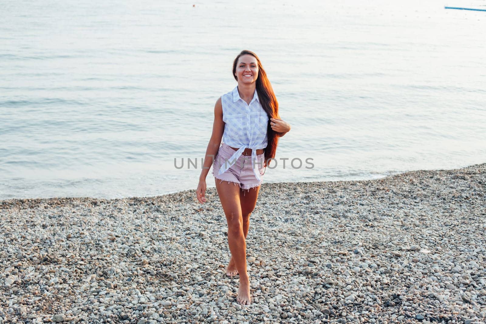 woman with long hair walks on beach by the sea