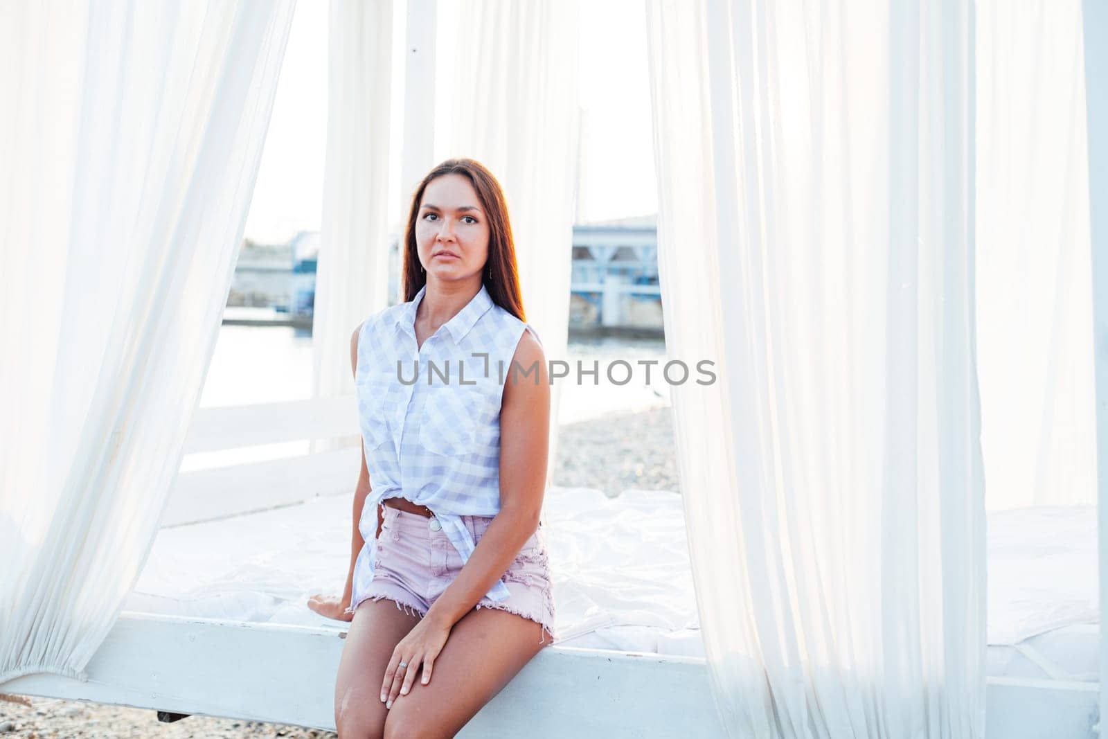 tanned woman with long hair sits white by Simakov