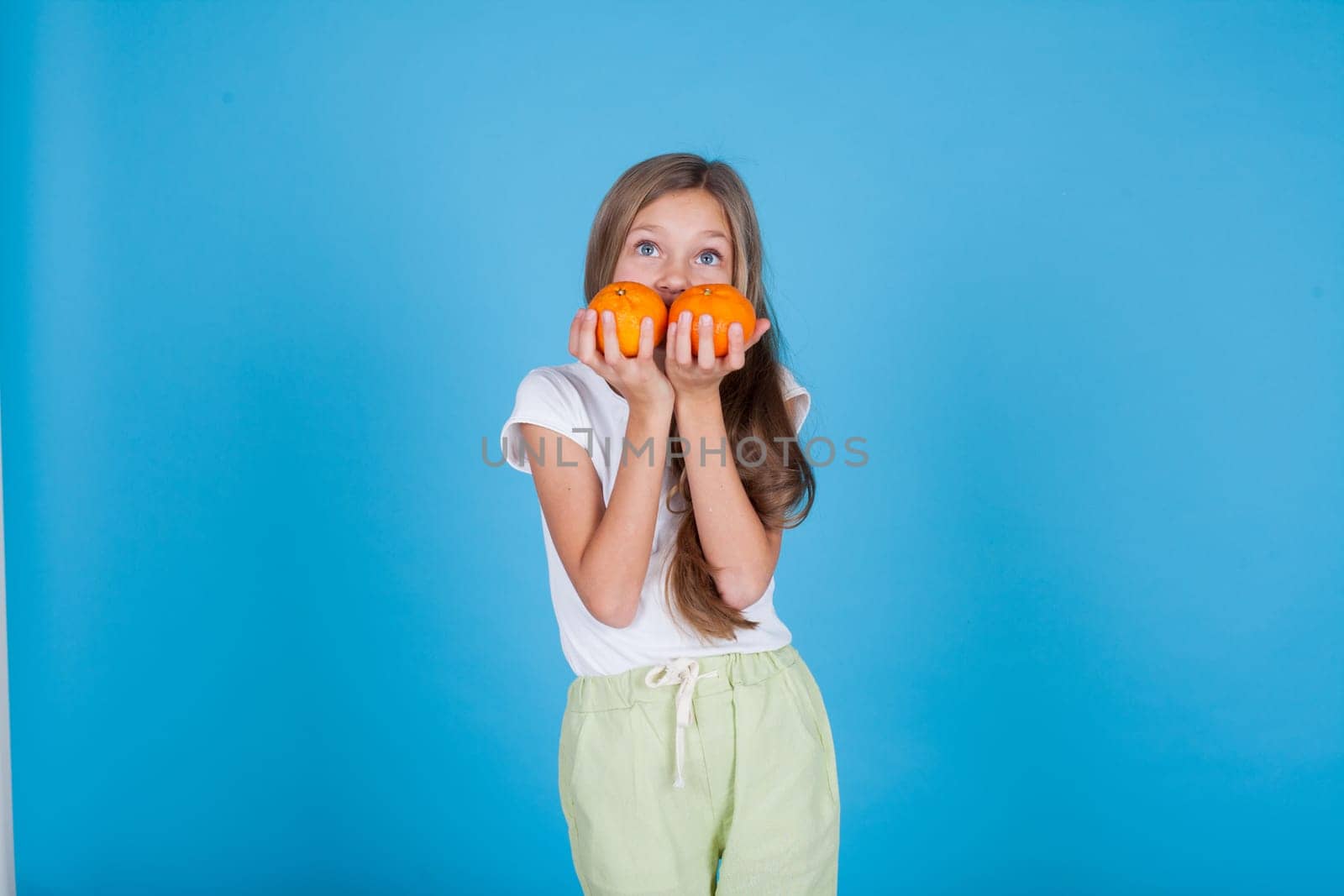 Beautiful little girl holding a ripe orange by Simakov