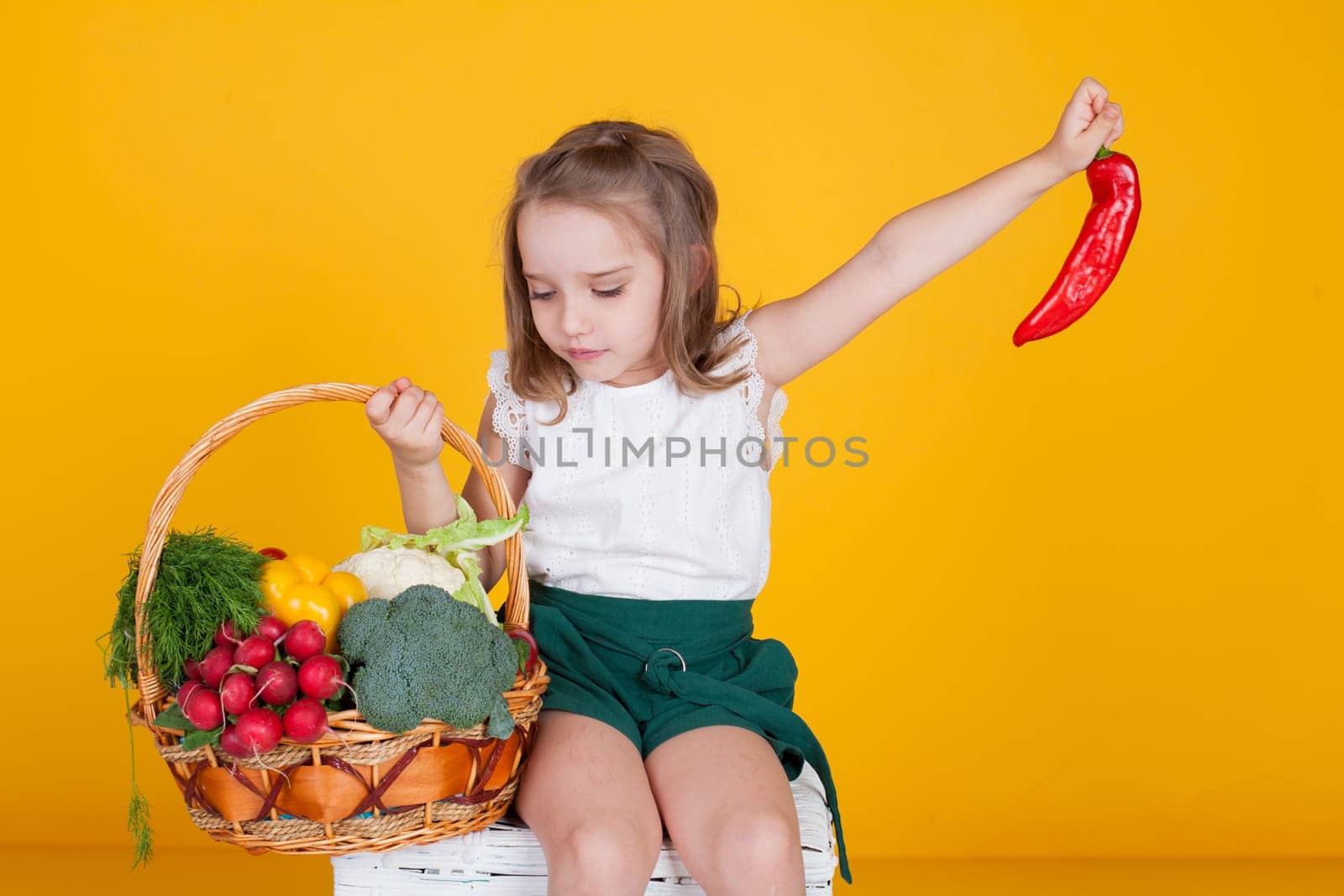 Beautiful little girl holding a basket of ripe vegetables by Simakov