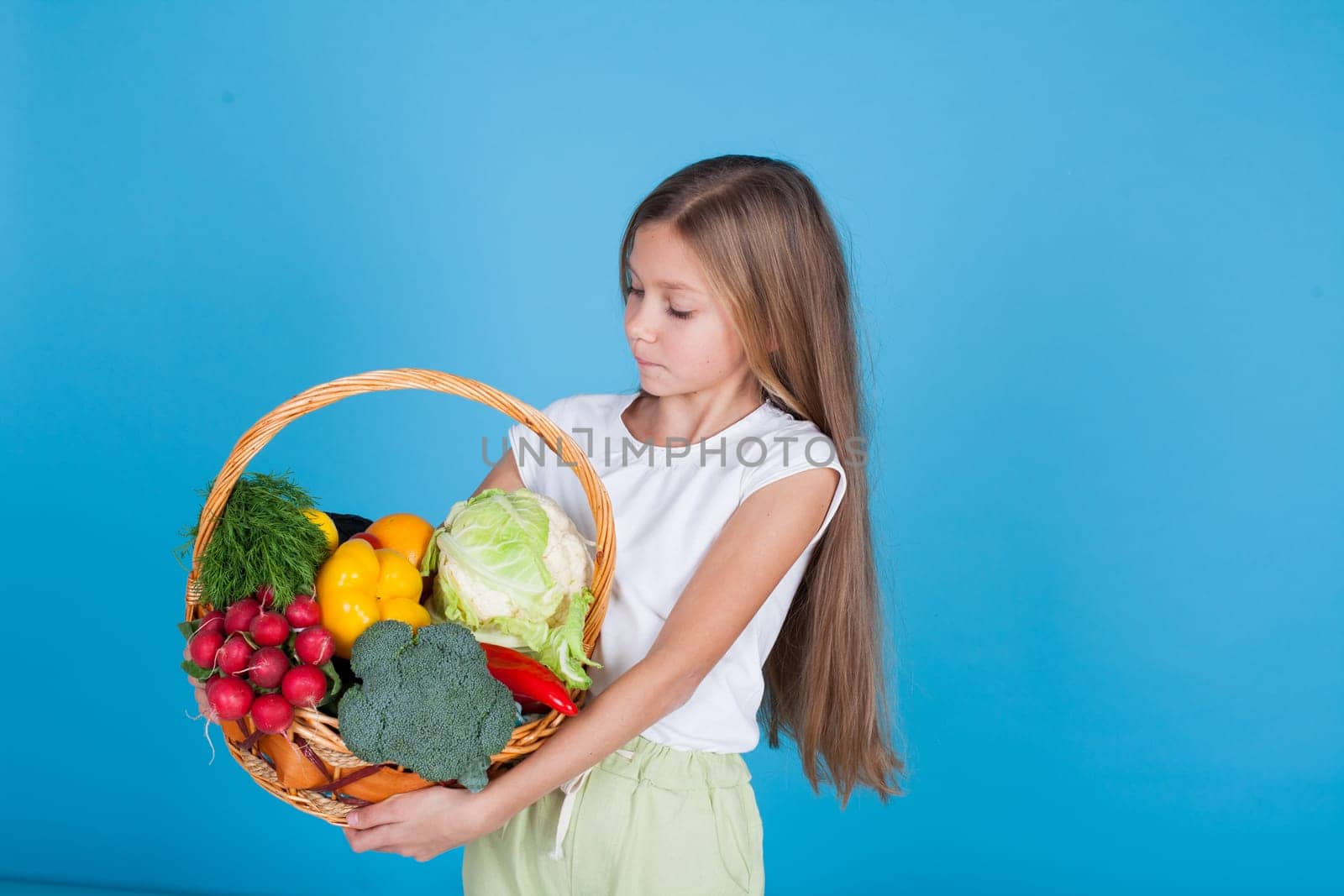 Beautiful girl holding a basket of ripe vegetables