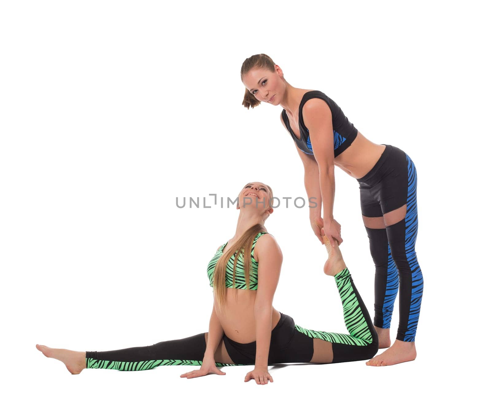 Smiling girl helps her friend to stretch, isolated on white