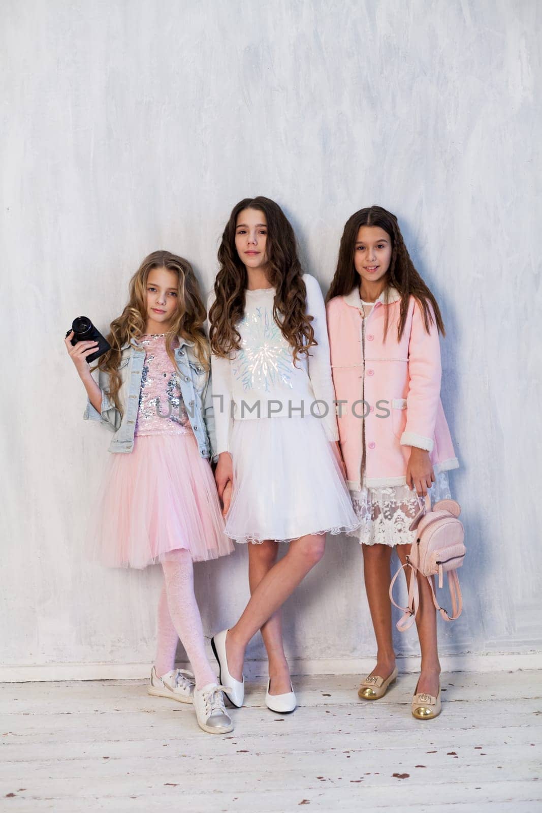 Three beautiful little girls with a camera at a photo shoot