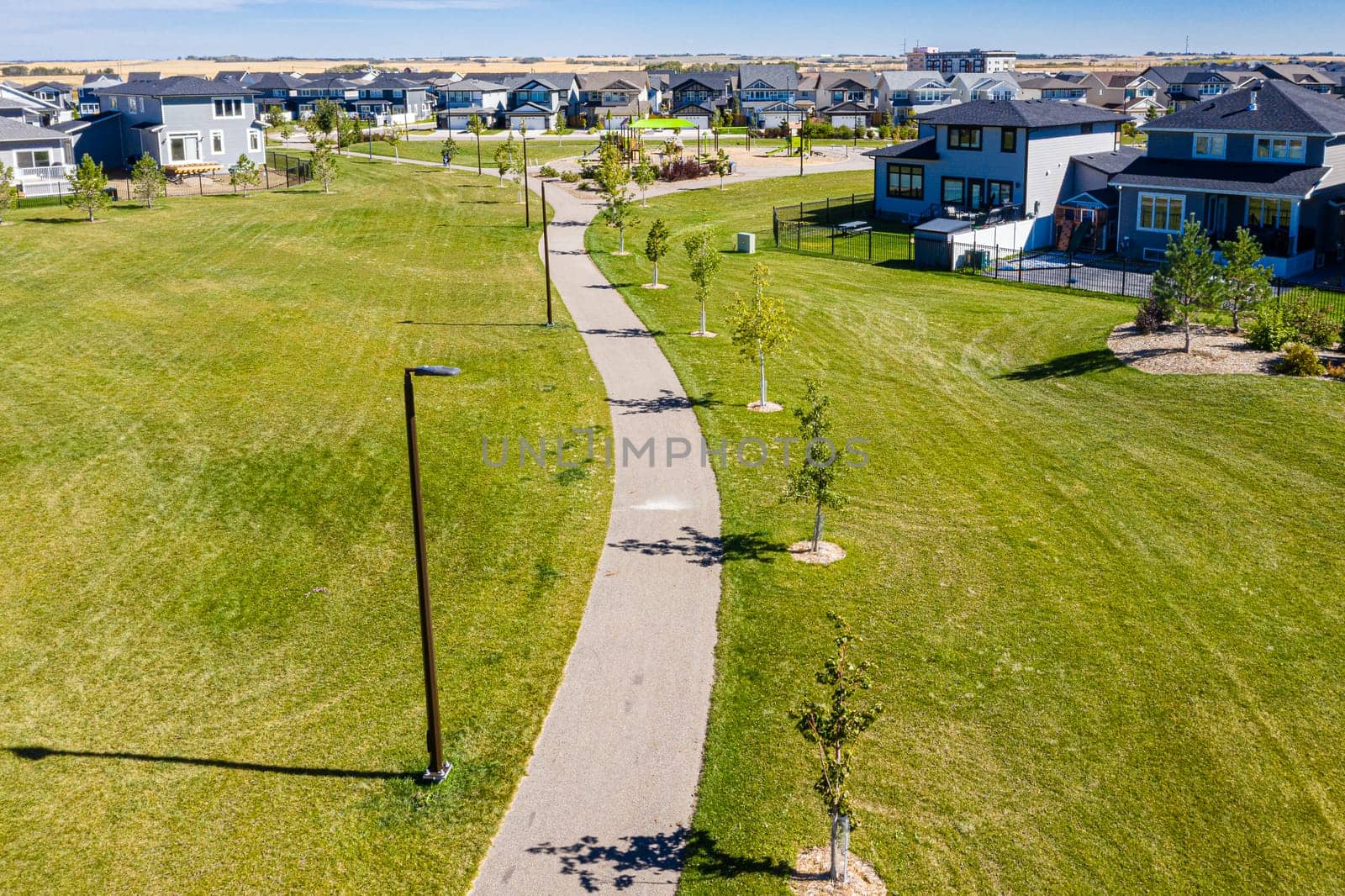 Experience the vibrant Brighton neighborhood in Saskatoon from the sky. This drone-captured image reveals the area's dynamic blend of modern living, lush parks, and community spirit, all from a stunning aerial viewpoint.
