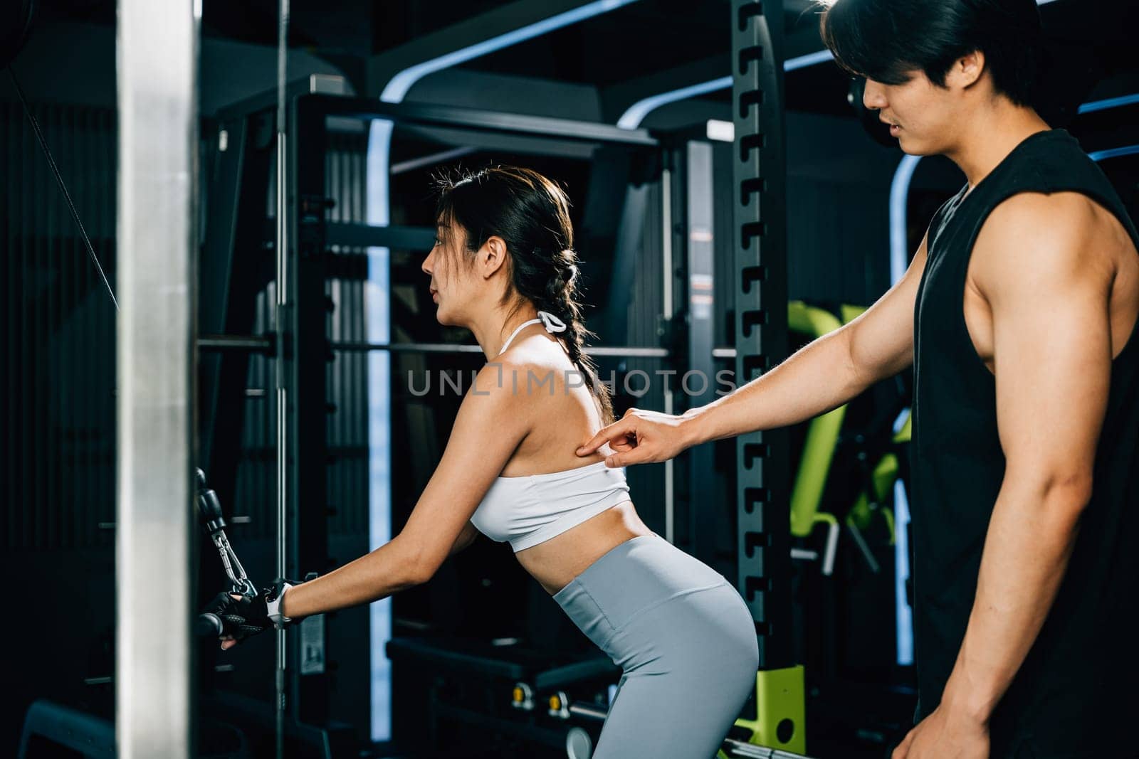 Trainer teaching proper form and technique for using a weight machine to train the biceps, helping his client achieve a stronger and healthier body. GYM healthy lifestyle concept