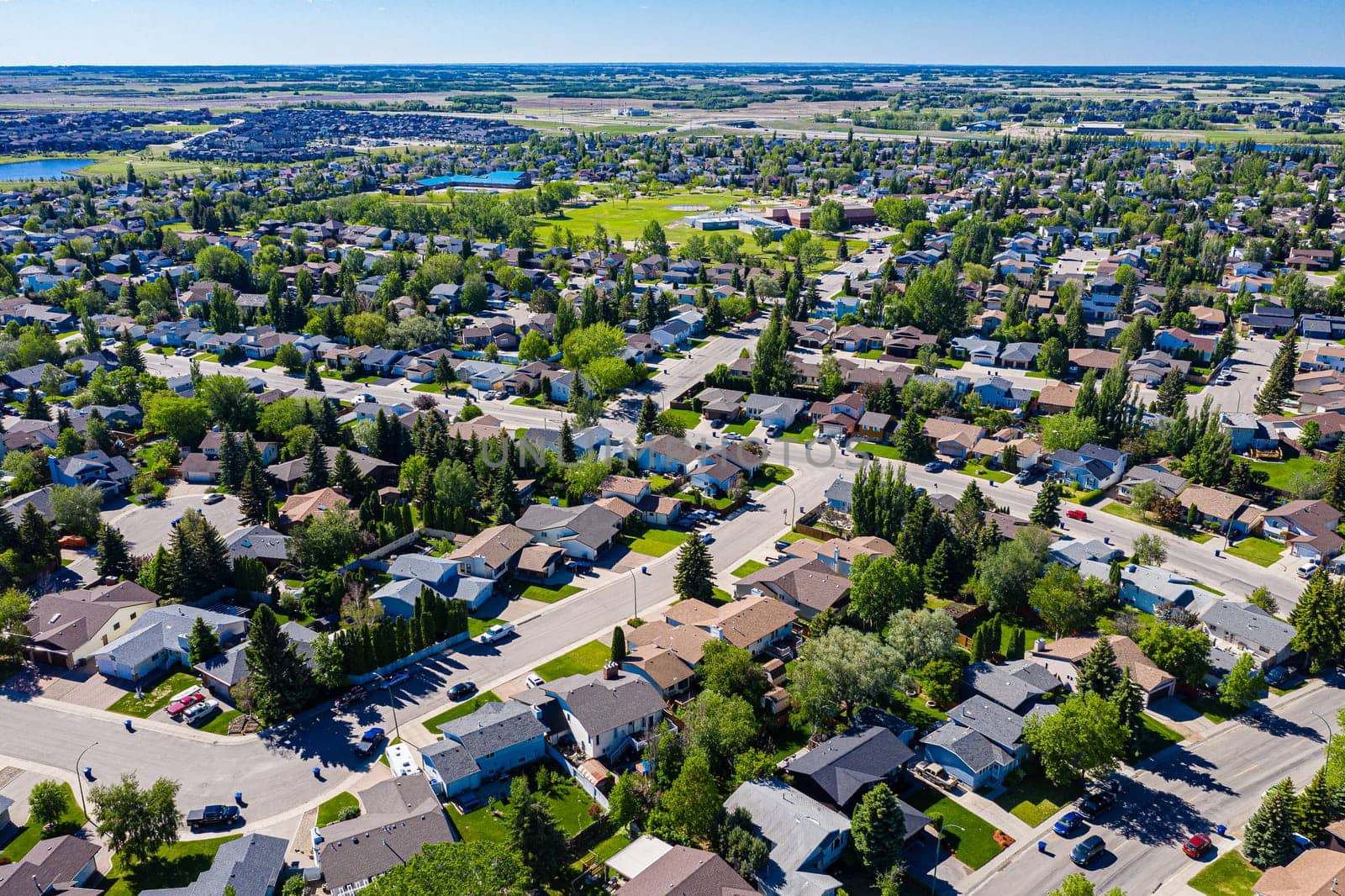 Experience the serene beauty of Lakeridge in Saskatoon from above. This drone image showcases the neighborhood's tranquil streets, lush green spaces, and the harmonious blend of urban and nature.