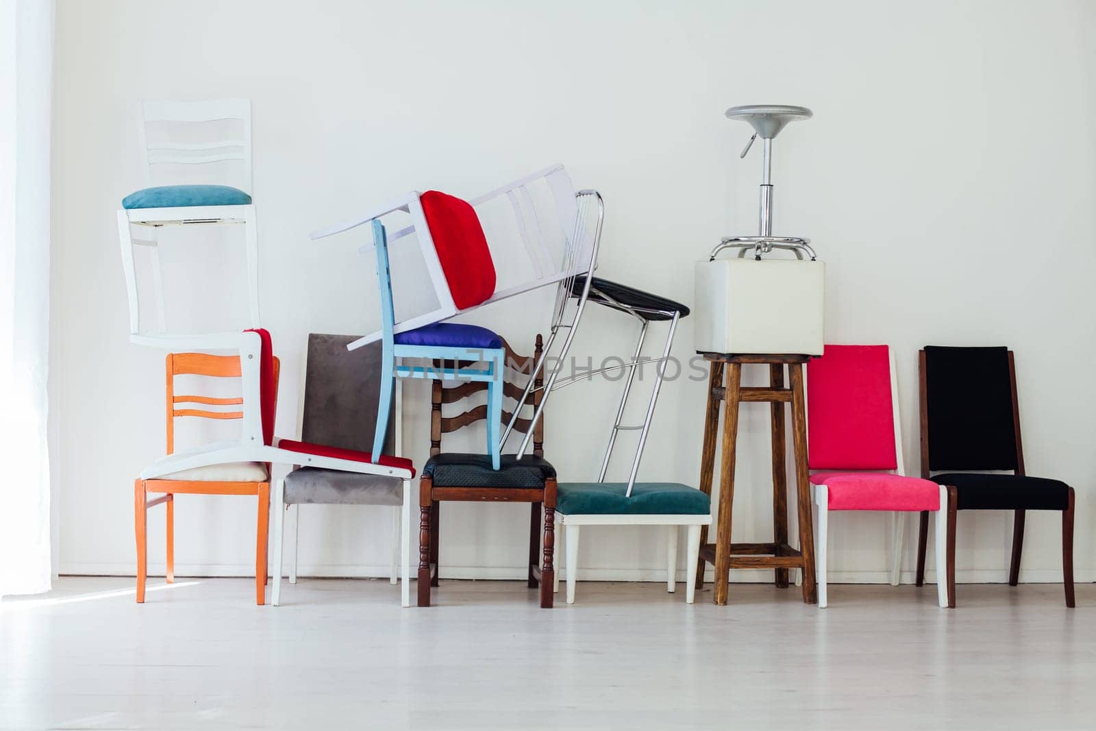 many different chairs in disarray in the interior of an empty white room